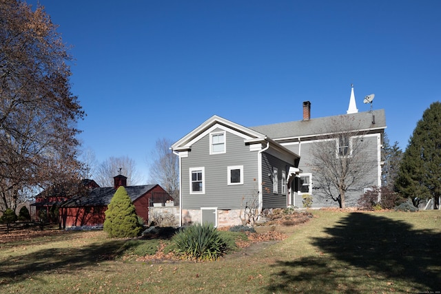 back of house with a yard and a chimney