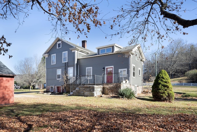 back of property with a lawn and a chimney