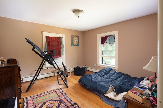 bedroom with a baseboard radiator and wood finished floors