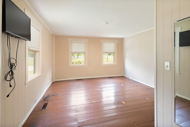 spare room with baseboards, visible vents, ornamental molding, and hardwood / wood-style floors