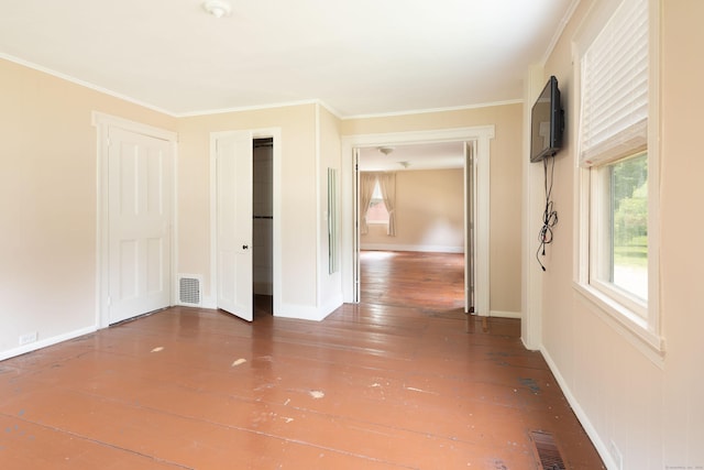 empty room with dark wood-type flooring, visible vents, ornamental molding, and baseboards