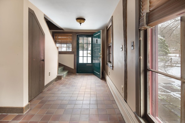 doorway featuring tile patterned flooring, stairway, and baseboards