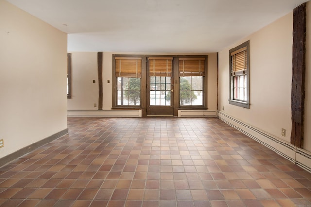 spare room featuring dark tile patterned floors and a baseboard heating unit