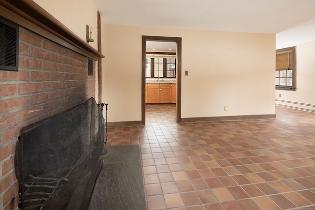 unfurnished living room featuring a baseboard radiator, a healthy amount of sunlight, dark tile patterned floors, and baseboards