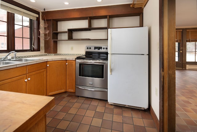 kitchen with open shelves, baseboard heating, freestanding refrigerator, stainless steel range with electric cooktop, and a sink