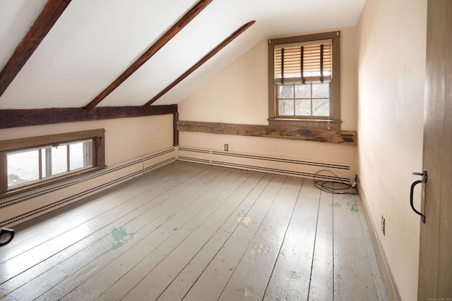 additional living space with lofted ceiling with beams, baseboard heating, wood-type flooring, and a healthy amount of sunlight