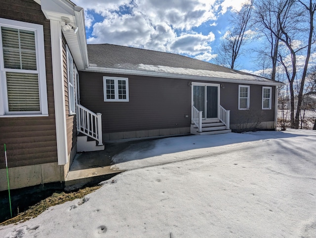 rear view of house featuring entry steps and a shingled roof