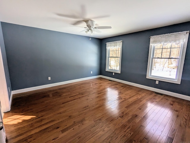 spare room with visible vents, dark wood finished floors, baseboards, and ceiling fan