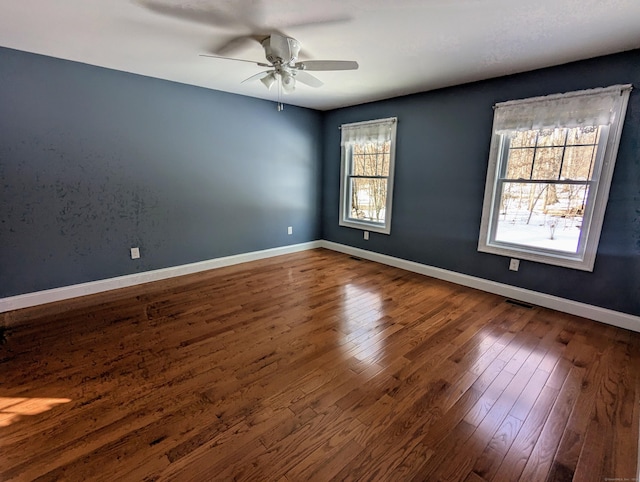 unfurnished room featuring wood-type flooring, visible vents, baseboards, and ceiling fan