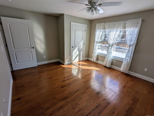 empty room with hardwood / wood-style floors, a ceiling fan, and baseboards