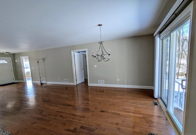 unfurnished dining area with a chandelier, dark wood finished floors, visible vents, and plenty of natural light