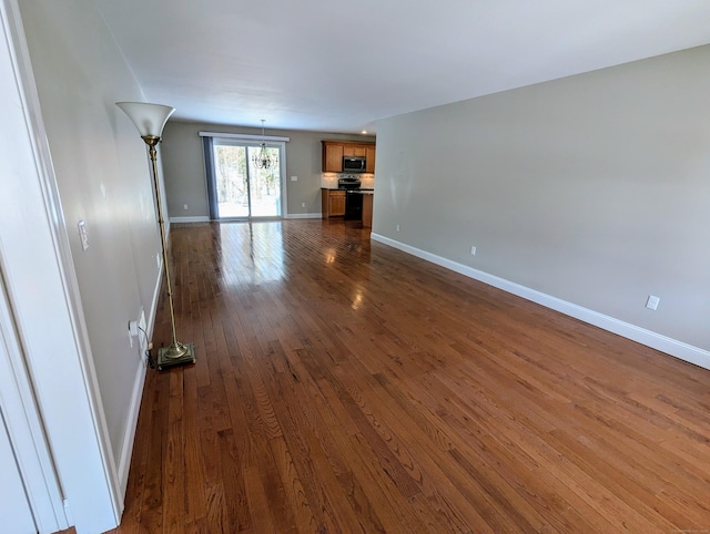 unfurnished living room featuring baseboards and dark wood-type flooring