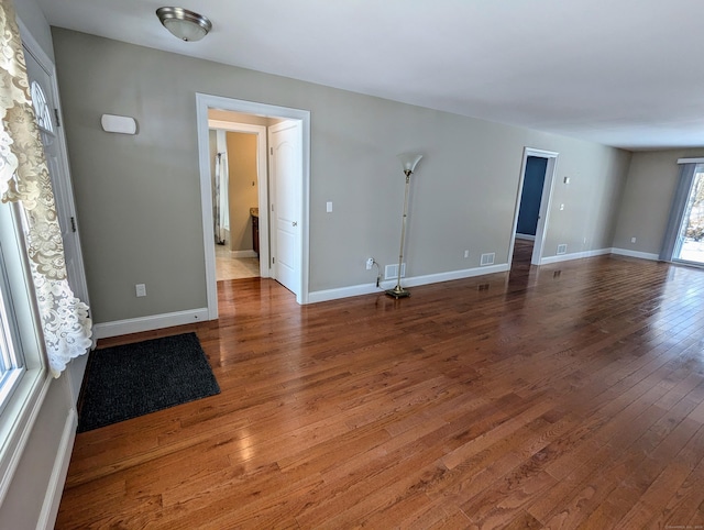 unfurnished room featuring visible vents, baseboards, and hardwood / wood-style floors