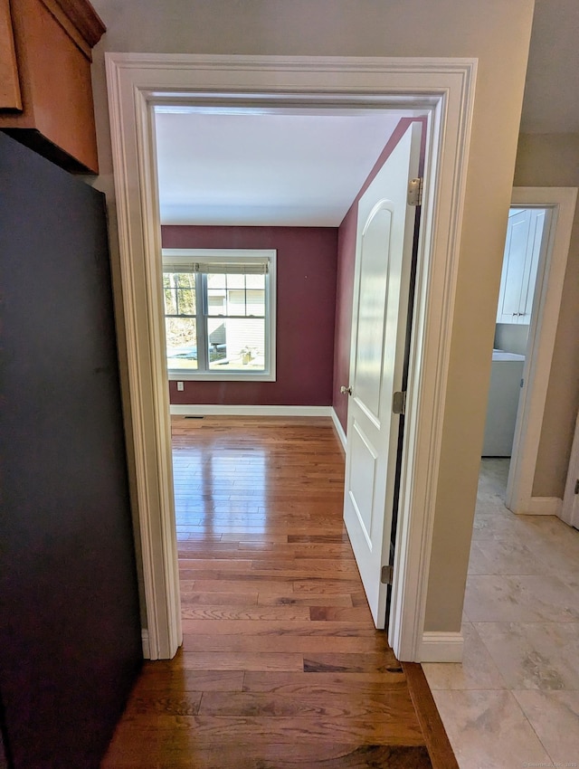 hallway with light wood-type flooring and baseboards