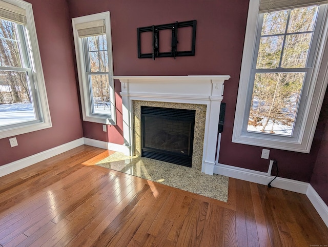 unfurnished living room with plenty of natural light, a premium fireplace, and baseboards