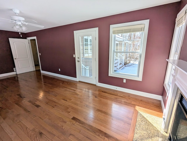 entrance foyer featuring wood-type flooring, a fireplace with flush hearth, a ceiling fan, and baseboards