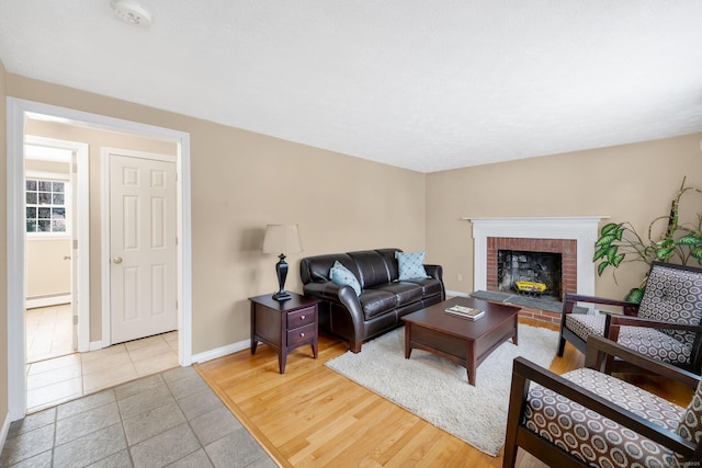 living area with a brick fireplace, baseboards, baseboard heating, and wood finished floors