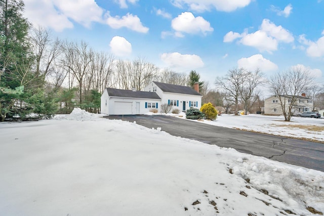 view of front facade with driveway, a chimney, and an attached garage