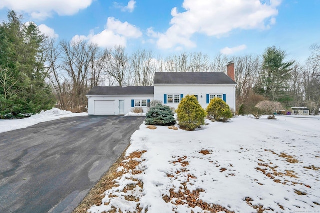 view of front of property featuring aphalt driveway, a chimney, and an attached garage