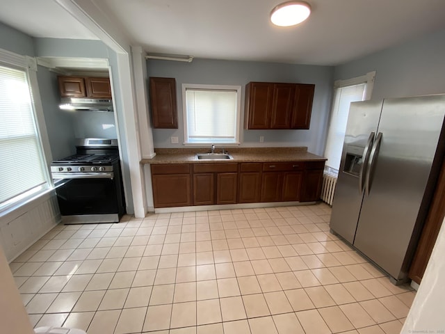 kitchen with light tile patterned floors, under cabinet range hood, stainless steel appliances, a sink, and a wealth of natural light