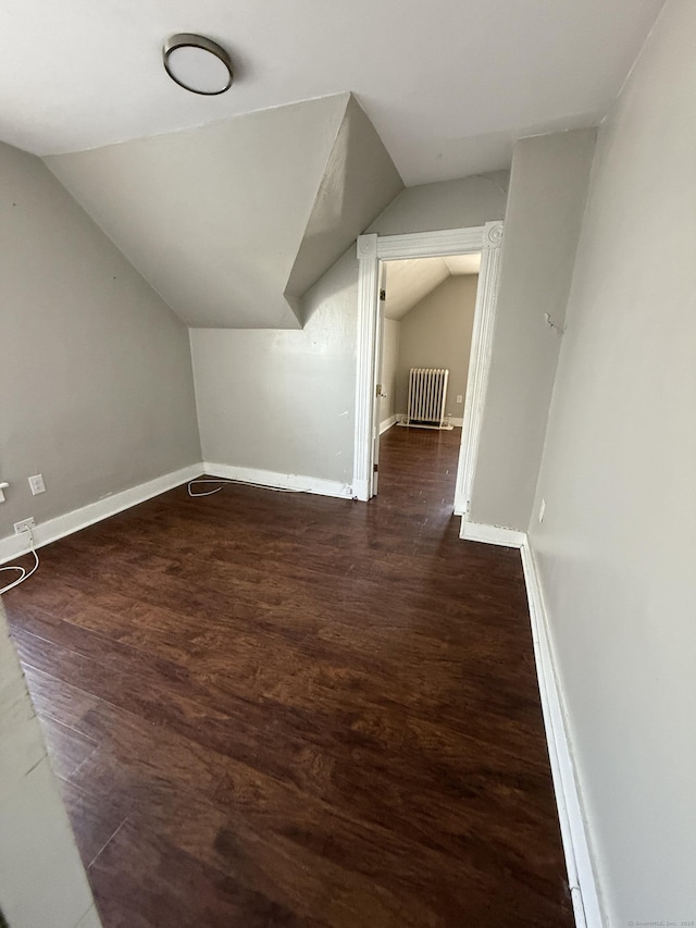 additional living space featuring dark wood-style floors, vaulted ceiling, and baseboards