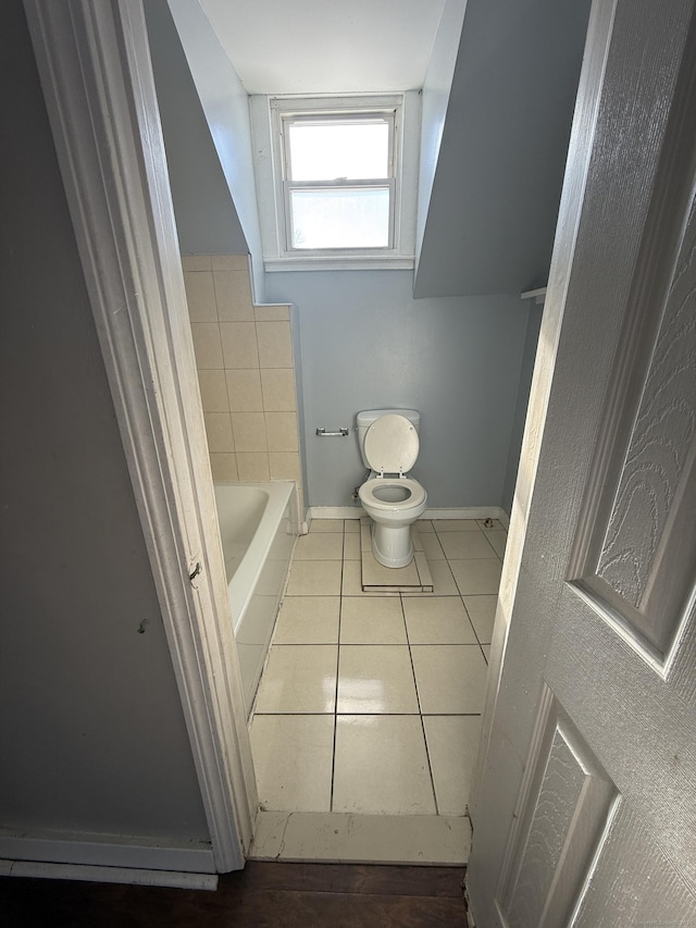 bathroom with a tub, tile patterned flooring, baseboards, and toilet