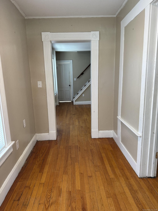 hall featuring hardwood / wood-style flooring, stairway, baseboards, and ornamental molding