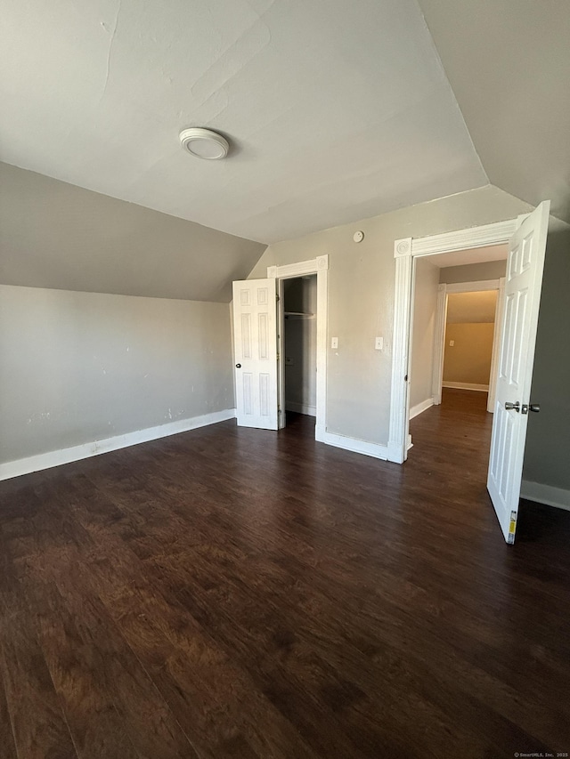 interior space with lofted ceiling, dark wood-style floors, and baseboards