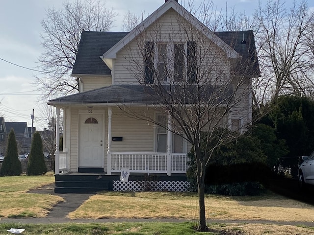 view of front of house featuring covered porch, a front lawn, and roof with shingles