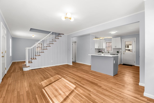 unfurnished living room featuring stairs, baseboards, light wood-style flooring, and crown molding