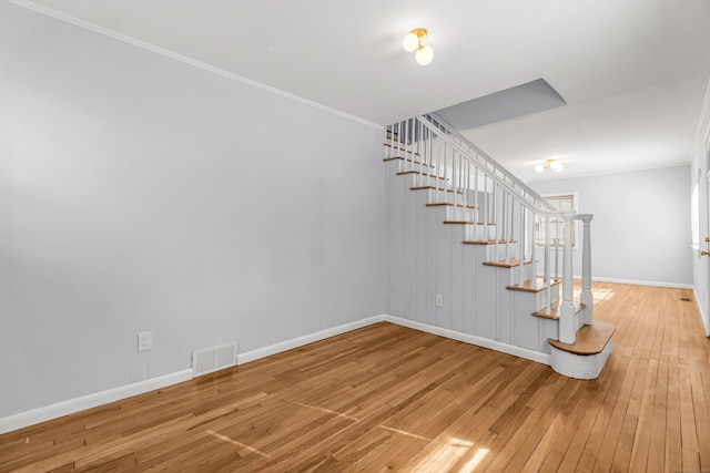 stairway with wood-type flooring, visible vents, crown molding, and baseboards