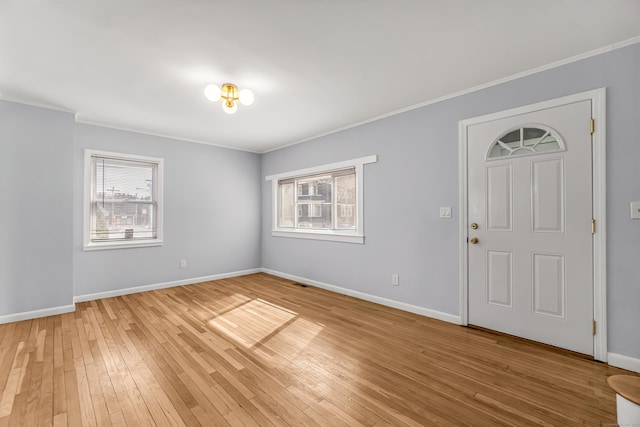 interior space featuring a healthy amount of sunlight, light wood-style floors, baseboards, and crown molding