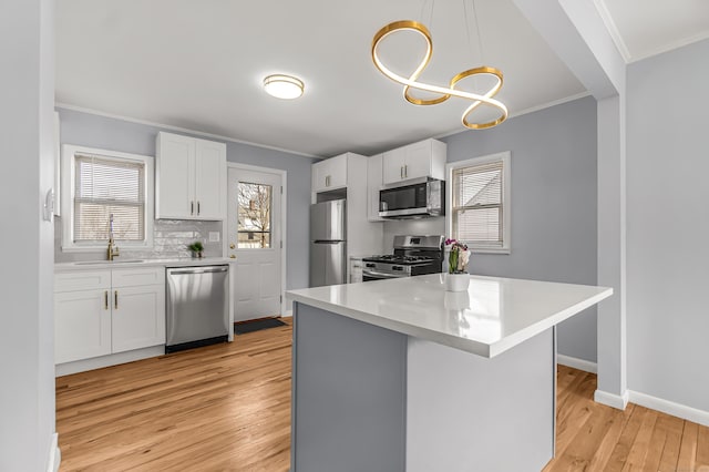 kitchen featuring stainless steel appliances, tasteful backsplash, ornamental molding, a sink, and light wood-type flooring