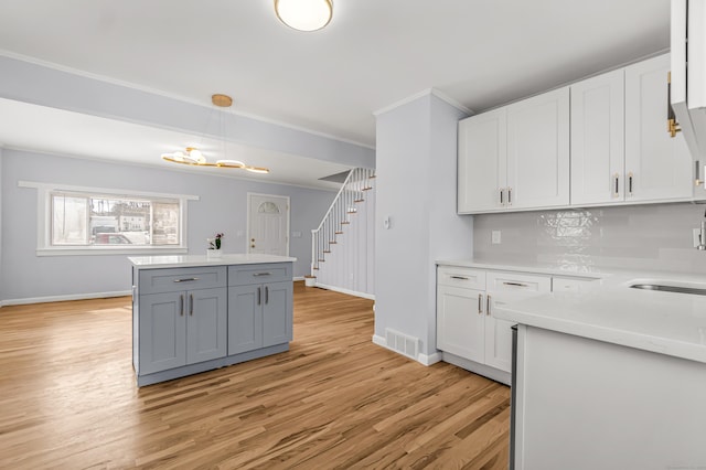 kitchen featuring visible vents, white cabinets, light wood-style flooring, light countertops, and backsplash