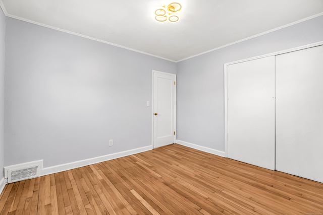 unfurnished bedroom with visible vents, baseboards, light wood-style floors, a closet, and crown molding