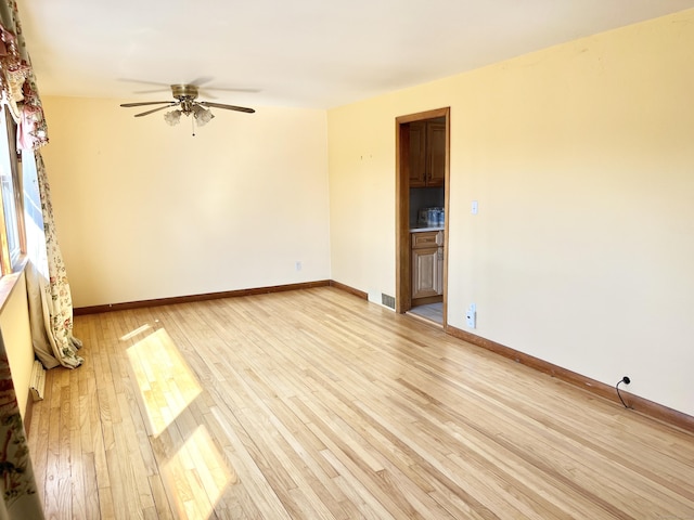 spare room with light wood-style floors, visible vents, baseboards, and a ceiling fan