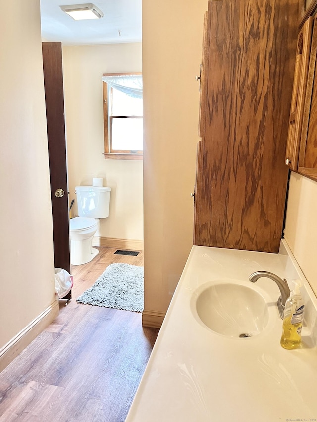 bathroom with baseboards, visible vents, toilet, wood finished floors, and vanity