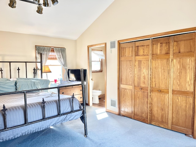 bedroom featuring visible vents, vaulted ceiling, light carpet, and ensuite bathroom