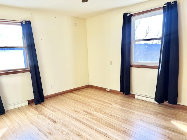 unfurnished room featuring ceiling fan, baseboards, baseboard heating, and wood finished floors