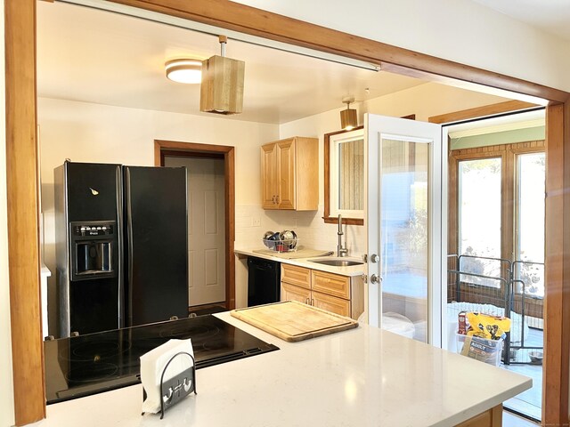 kitchen with black appliances, backsplash, a sink, and light countertops