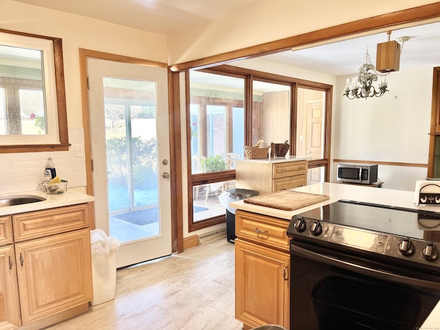 kitchen with electric stove, tasteful backsplash, light countertops, stainless steel microwave, and an inviting chandelier