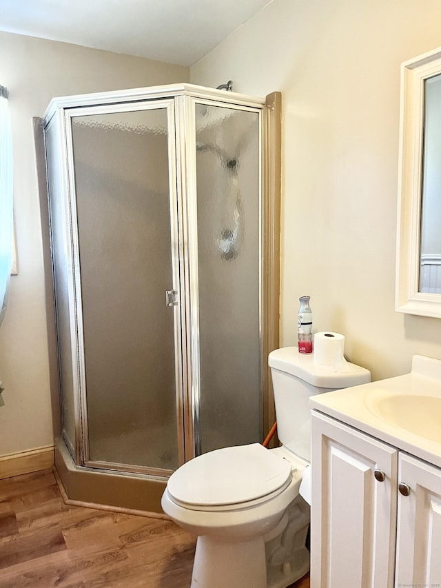 bathroom with toilet, a stall shower, wood finished floors, and vanity