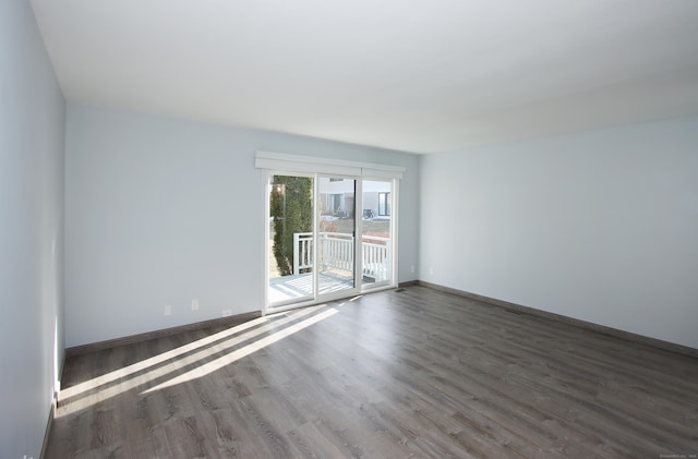 empty room with dark wood-type flooring and baseboards