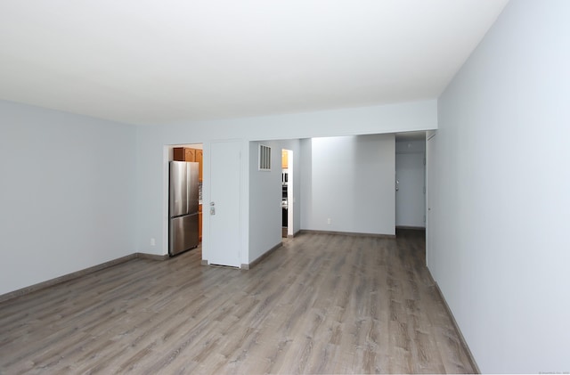 spare room featuring light wood-type flooring, visible vents, and baseboards