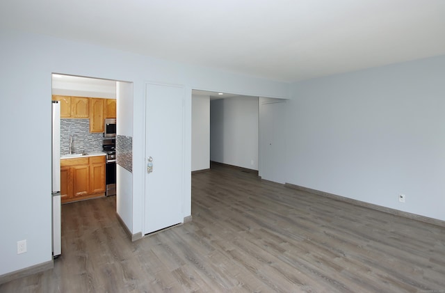 empty room with a sink, baseboards, and wood finished floors