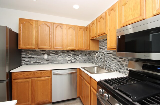 kitchen with recessed lighting, light countertops, backsplash, appliances with stainless steel finishes, and a sink