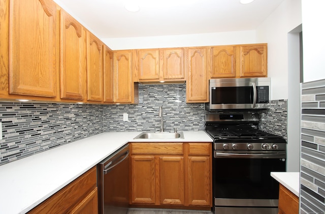 kitchen with light countertops, appliances with stainless steel finishes, a sink, and decorative backsplash