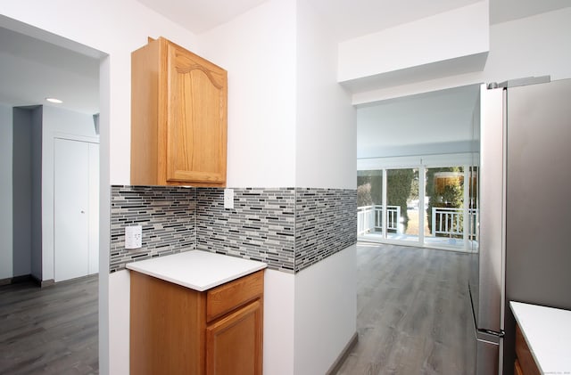 kitchen featuring backsplash, light countertops, wood finished floors, and freestanding refrigerator