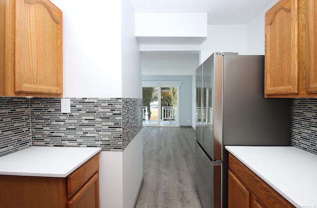 kitchen with light countertops, decorative backsplash, light wood-style flooring, and stainless steel fridge with ice dispenser