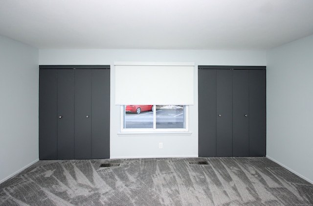 unfurnished bedroom featuring visible vents and dark carpet